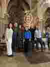 Group of smiling attendees of a B Local event standing inside a cathedral beneath arched ceilings, with a B Corp logo illuminated on the stone wall in the background.