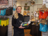 Sarah Jordan, founder of YOU Underwear holding a box of product at their physical store, with underwear displays in the background.